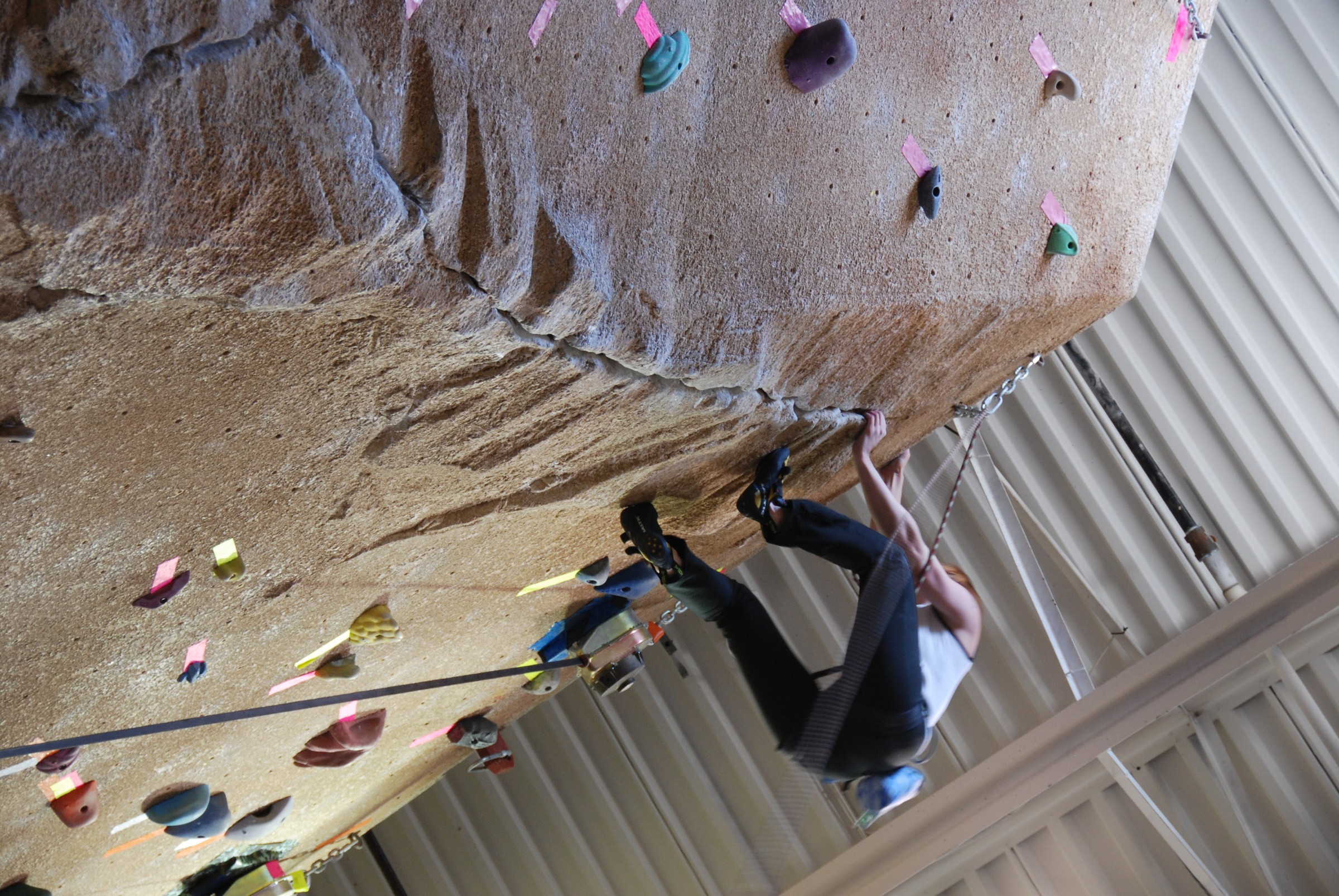 Climber on overhang with StoneCraft rock-textured climbing wall