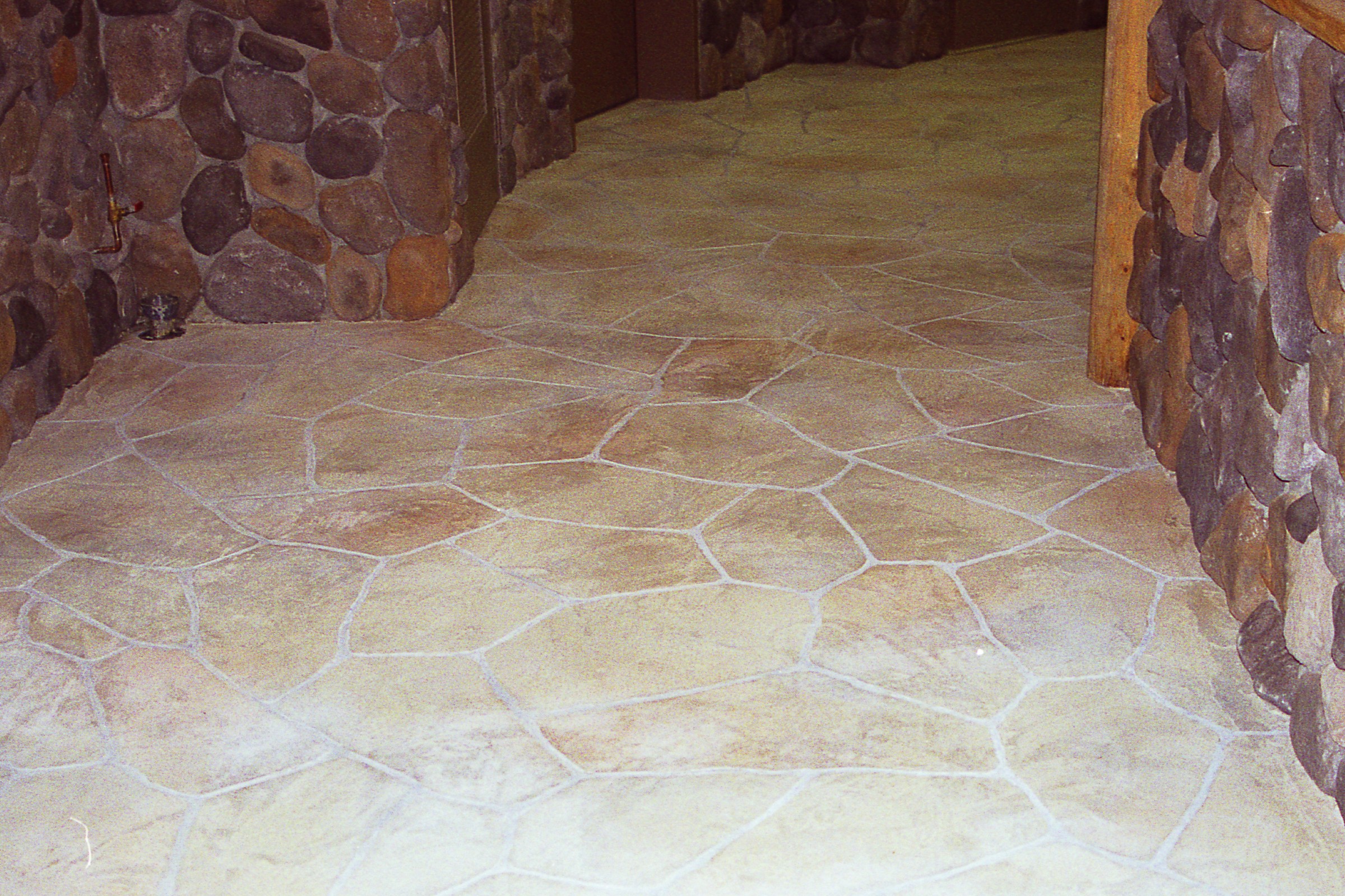 Lodge hallway with flagstone-pattern StoneCraft flooring and river rock walls