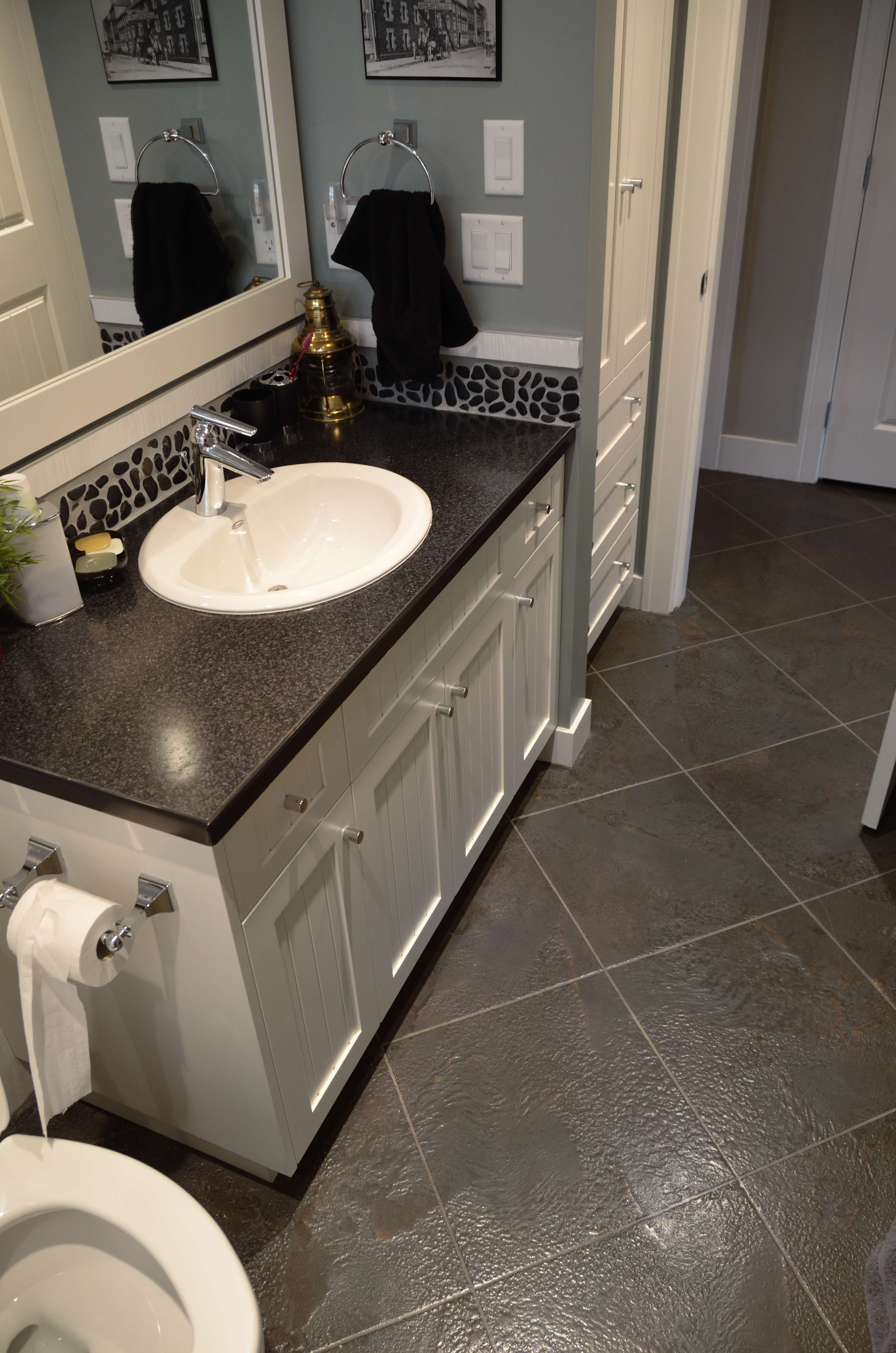 Bathroom vanity with dark StoneCraft slate flooring and pebble backsplash