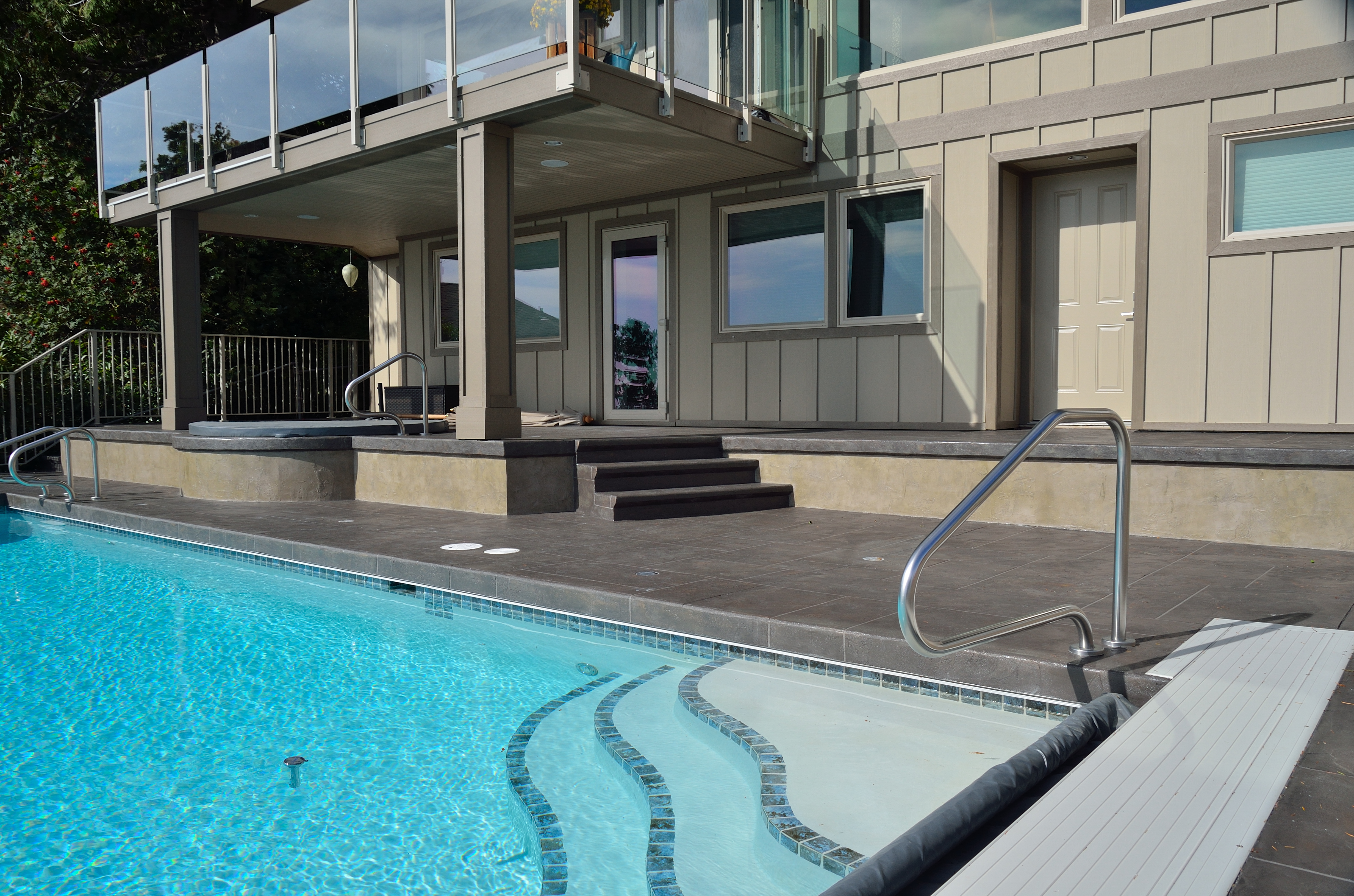 Elevated pool deck with StoneCraft slate surfacing and glass railings