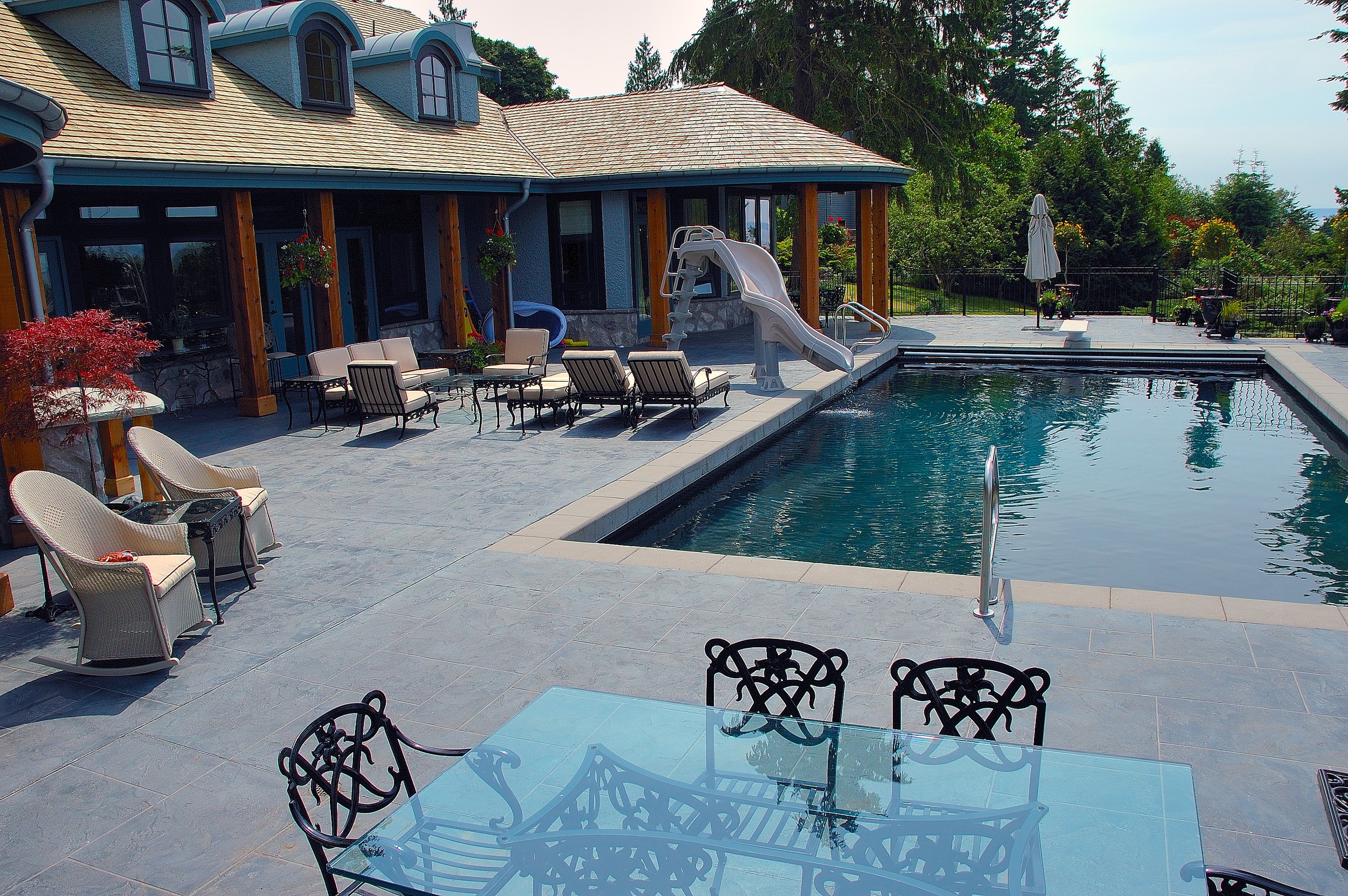 Luxury pool with StoneCraft slate deck, slide, and patio seating