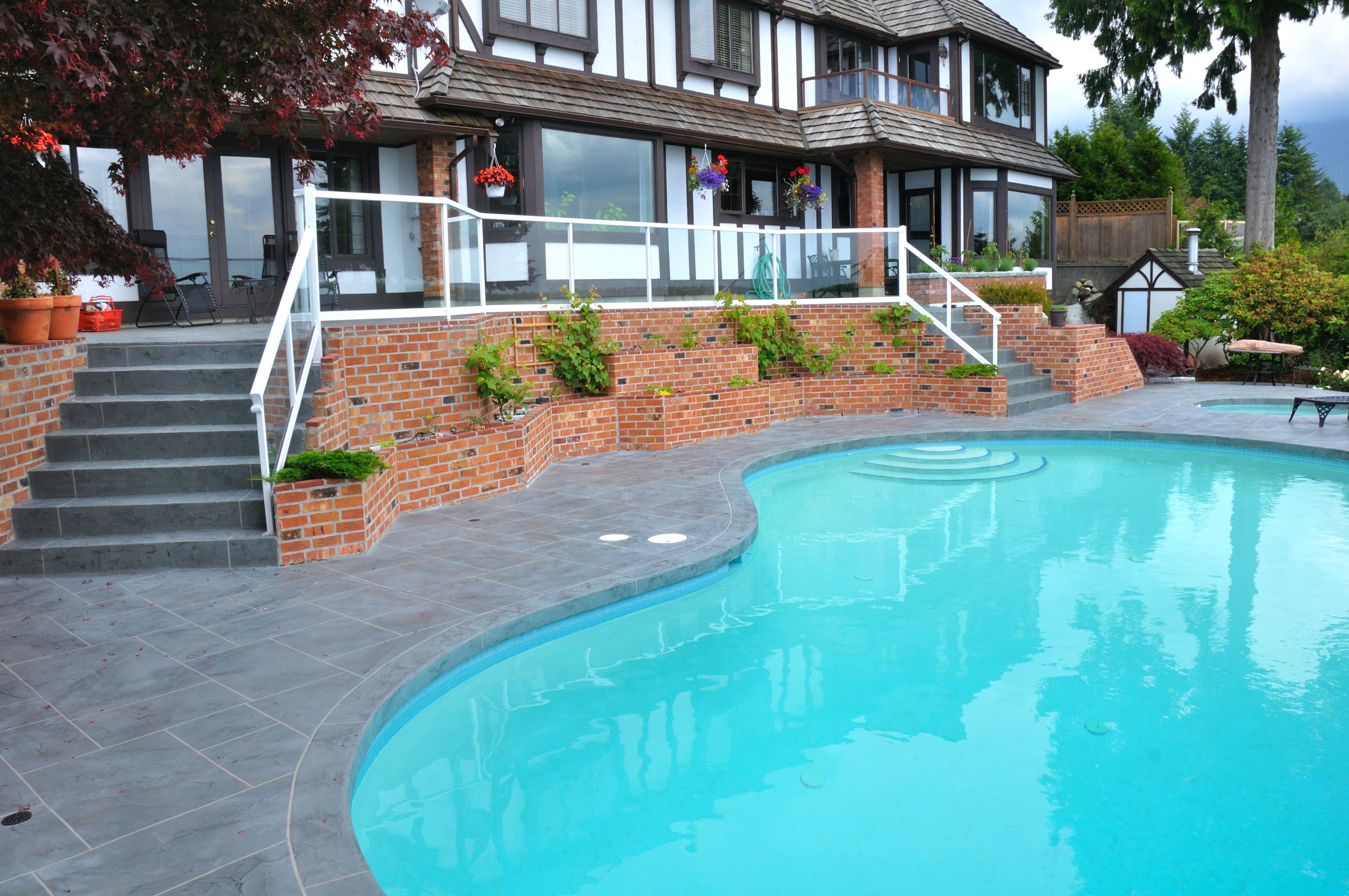 Curved pool with dark StoneCraft decking and brick retaining walls