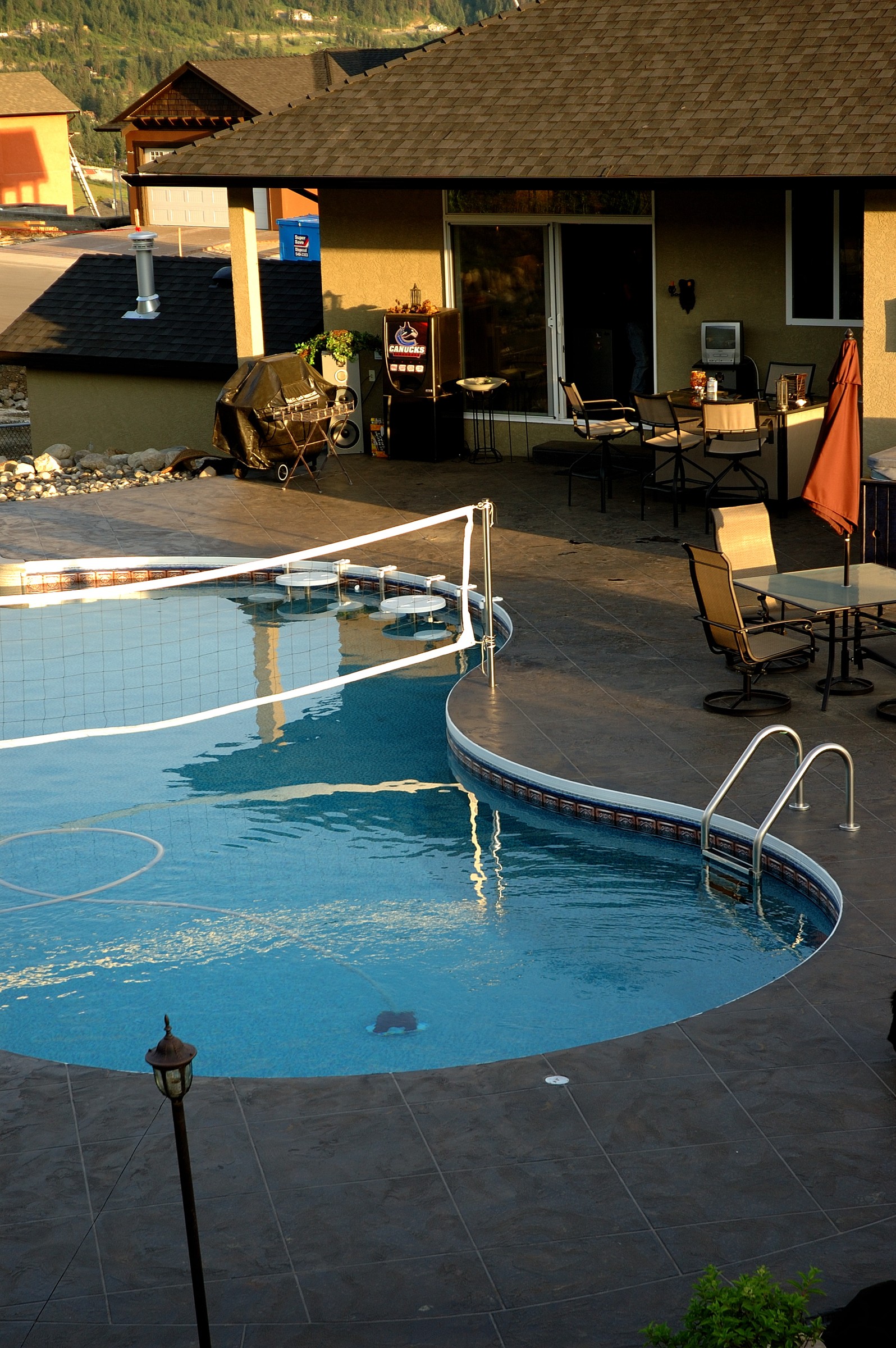 Dual pool and spa with dark StoneCraft decking and evening lighting